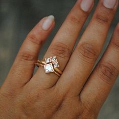 a woman's hand with a gold ring and two square shaped diamonds on it