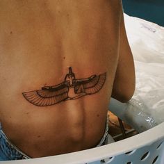 a woman with a tattoo on her stomach is sitting in front of a laundry basket