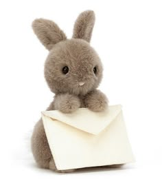 a stuffed rabbit holding an envelope in its paws