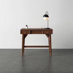 a wooden desk with a lamp on top and a white wall in the back ground