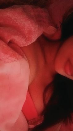 a close up of a person laying in bed with a pink blanket on top of their head