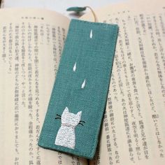 a bookmark with a cat on it sitting on top of an open book,