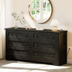 a black dresser with a round mirror above it