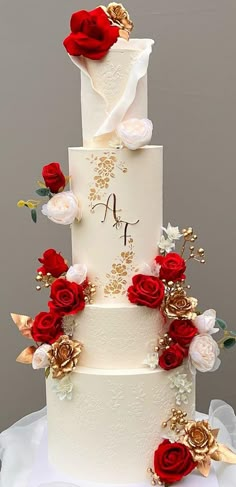 a three tiered wedding cake with red and white flowers