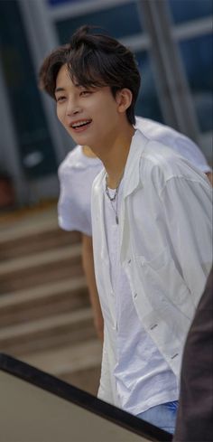 the young man is wearing a white shirt and smiling at someone in front of him