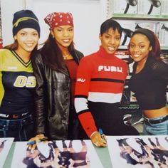 three young women standing next to each other in front of a table with pictures on it