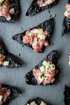 several pieces of food are arranged on top of a gray surface with scallions and garnishes