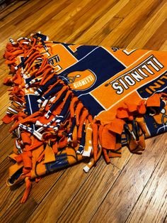 an orange and blue blanket laying on top of a wooden floor