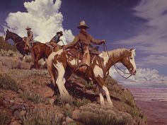 two men riding horses on a rocky hill with clouds in the sky behind them and one man wearing a cowboy hat