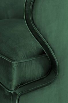 an upholstered green velvet chair with curved arms