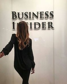 a woman is walking in front of a business insider sign with her hands out to the side