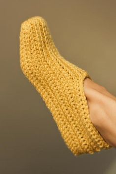 a person's hand wearing a yellow knitted mitt