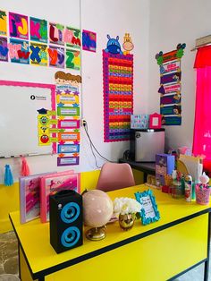 a yellow desk topped with lots of colorful items and posters on the wall behind it