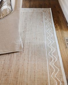 a beige and white rug on the floor next to a couch