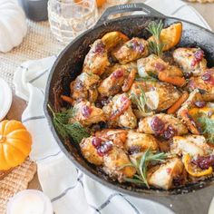 a pan filled with chicken and cranberry oranges on top of a table