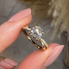 a close up of a person's hand holding a ring with a diamond on it