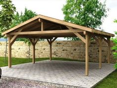 a large wooden gazebo sitting on top of a stone patio next to a brick wall