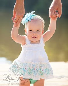 a baby girl holding her mother's hand on the beach