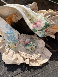 two pieces of cloth sitting on top of a wooden table next to a basket with flowers