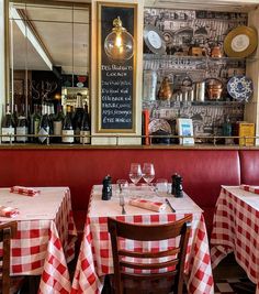 a restaurant with red and white checkered tablecloths, wine bottles on the wall