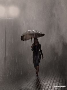 a woman is walking in the rain with an umbrella and she has dark clothing on