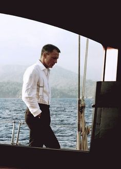 a man standing on the deck of a boat looking at something in the water behind him