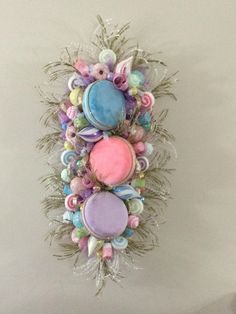 a decorative wall hanging made out of different colored buttons and feathers on a white wall