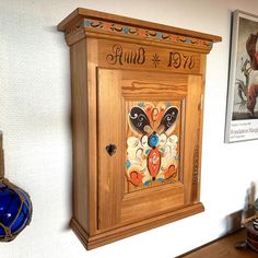 a wooden cabinet with an ornate design on the front and sides, hanging from a wall