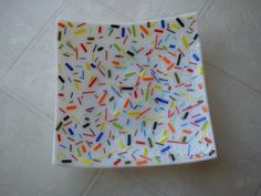 a white plate with sprinkles on it sitting on a tile floor next to a wall