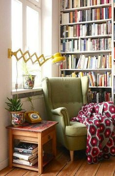 a green chair sitting in front of a window next to a book shelf filled with books