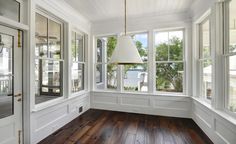 an empty room with wood floors and white walls, large windows on the far wall