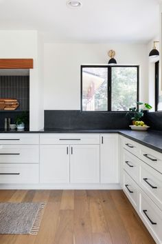 a kitchen with white cabinets and black counter tops