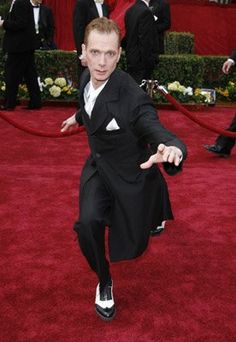 a man in a tuxedo is running on the red carpet