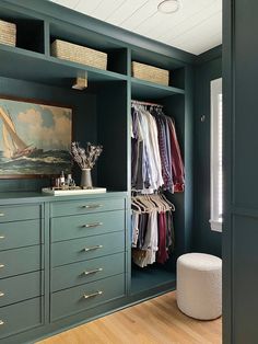 a walk in closet with lots of drawers and clothes hanging on the wall next to it