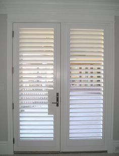 two white doors with blinds on them in a room