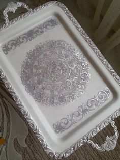 a decorative white tray with intricate designs on the edges and sides, sitting on a carpeted floor