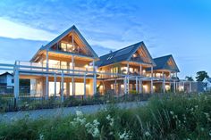 a large house sitting on top of a lush green hillside next to tall grass and flowers