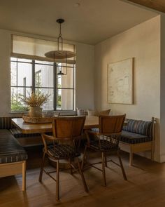 a dinning room table with chairs and a bench in front of a large window