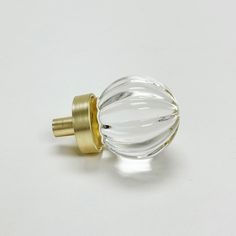 a glass door knob with a gold top on a white surface in front of a plain background