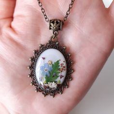 a close up of a person's hand holding a necklace with flowers on it