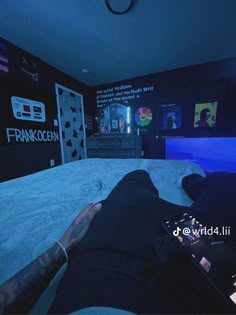 a person laying on top of a bed in a room with black walls and blue lighting