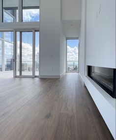 an empty living room with wood floors and large windows looking out onto the cityscape