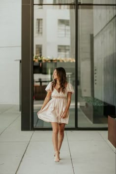 a woman walking down the sidewalk in front of a building