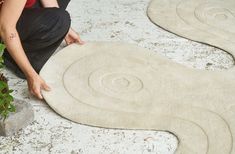 a person kneeling down on the ground working on a piece of art that looks like a snake