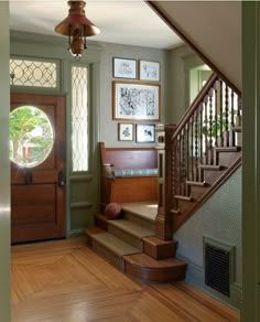 an entryway with stairs and pictures on the wall above it, along with hardwood flooring