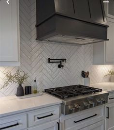 a stove top oven sitting inside of a kitchen next to white cupboards and drawers