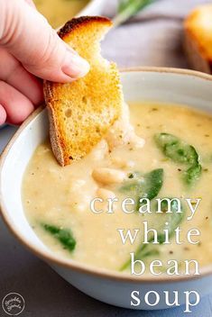 a hand dipping a piece of bread into a bowl of soup with the words tuscann white bean soup