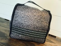 a black and white bag sitting on top of a wooden floor next to a wall