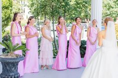 a group of women standing next to each other in front of a white building with trees