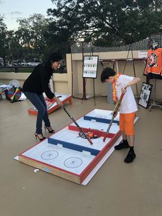 two people are playing with an inflatable hockey game on the ground while another woman watches